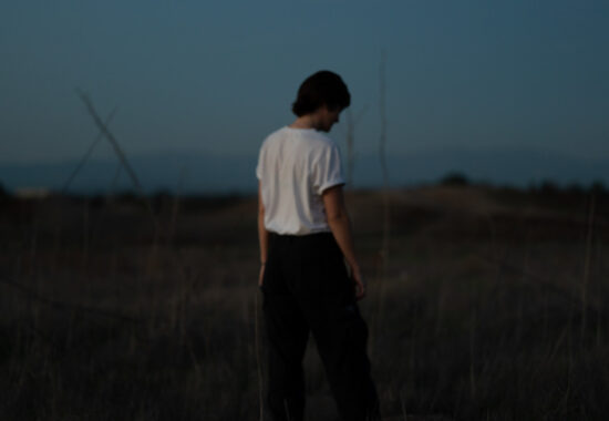 Out of focus musician at dusk looking at ground with hands in pockets